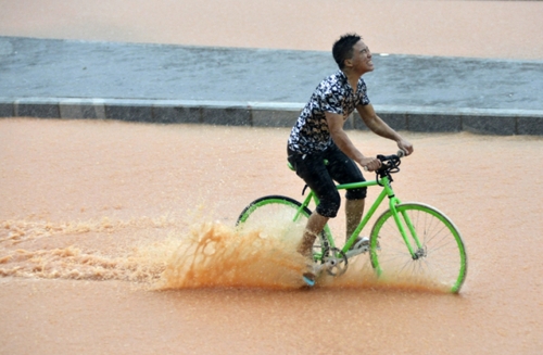 5月11日，一名行人在深圳街頭冒雨騎行。