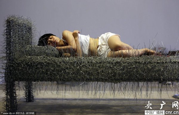 2014年8月11日，北京，中國女藝術(shù)家周潔在北京現(xiàn)在畫廊的展廳睡在一個(gè)未完成的鐵絲床上，這一藝術(shù)項(xiàng)目被命名為“36天”，而這36天里，她可以正常進(jìn)食、洗漱、如廁，以及玩手機(jī)等。
