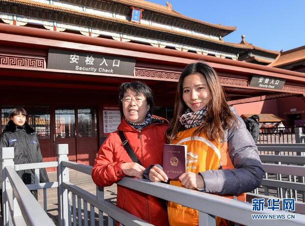 12月3日，一名教師（右）在故宮博物院入口處展示教師資格證。