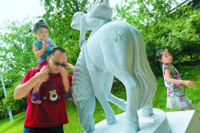 排隊(duì)購買“猴年馬月”特色郵品后，人們喜歡摸一摸“馬上封侯”的雕塑，為家人祚福。