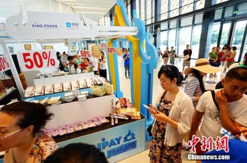 資料圖：某消費(fèi)者在線下商品展臺(tái)前選購(gòu)。