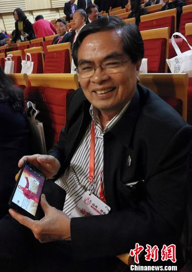 泰國華文民校協(xié)會中文秘書、泰國明滿學(xué)校校長陳松向記者展示學(xué)生參加“漢語橋”比賽的照片?！罱苡?攝