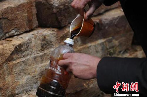 一名村民將不明液體灌入透明飲料瓶內(nèi)。　　孟梅 攝
