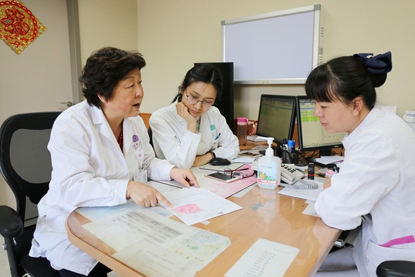 廖秦平在門診中和醫(yī)生一起討論病例。楊欣 攝