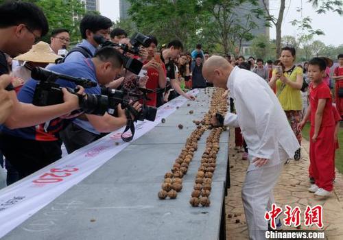 黎偉軍手劈核桃現(xiàn)場吸引不少人圍觀?！〕叹皞?攝