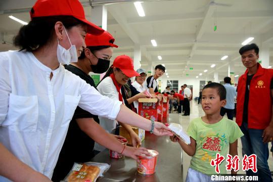 8月24日，志愿者在濰坊壽光市營(yíng)里鎮(zhèn)第二初級(jí)中學(xué)安置點(diǎn)為災(zāi)民發(fā)放救援物資?！×籂?攝