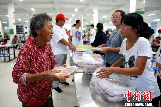 8月24日，志愿者在濰坊壽光市營(yíng)里鎮(zhèn)第二初級(jí)中學(xué)安置點(diǎn)為災(zāi)民發(fā)放救援物資。　梁犇 攝