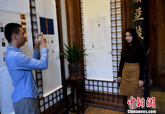 一名“90后”女大學(xué)生篆刻作者在自己創(chuàng)作的作品前留影?！∮浾邉⒖筛?攝
