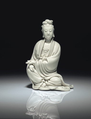 明十七世紀(jì)初 德化白釉書卷觀音坐像 《何朝宗》葫蘆形印款，高8 58 寸 (21.9公分)。估價：60,000-80,000美元。此拍品于2018年9月13至14日在佳士得紐約亞洲藝術(shù)周之中國瓷器及工藝精品拍賣中呈獻。