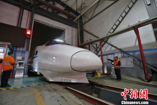 一列動車組駛入車庫，機械師位列兩邊檢查車體外觀?！《〔?攝