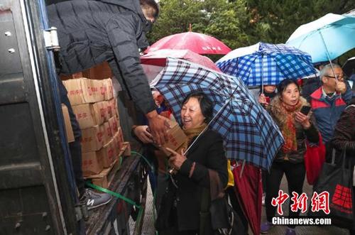 資料圖：上海百名居民在雨中排成一條長(zhǎng)龍，領(lǐng)取剛到貨的秭歸臍橙。供圖