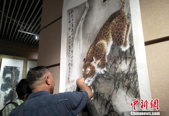 觀眾欣賞六尺國(guó)畫(huà)掛軸《豹子覓泉圖》。主辦方供圖