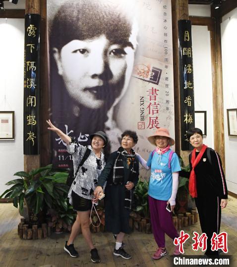 觀(guān)眾在展出的冰心青年時(shí)期黑白老照片前合影?！∮浾邉⒖筛?攝
