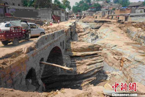此次山洪將臺頭村公路連同下面的垃圾完全沖走，暴露出古河道當(dāng)年的面貌。　張帆 攝